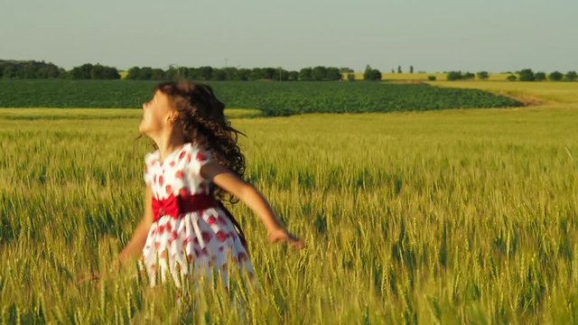 Happy child in the field. A little girl is spinning in a field of wheat.