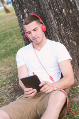 Fototapeta premium Young man with headphones, holding a tablet.