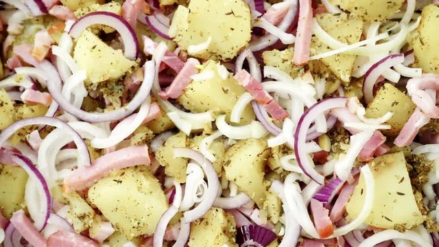 Peeled potatoes with spices, becon meat and onion slices ready to be roasted close up. Food background. Rack focus 4K ProRes HQ codec
