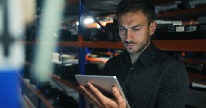 smart young attractive businessman with tablet pc at warehouse