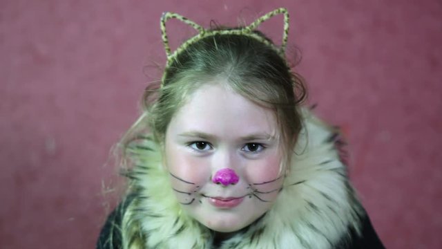 Little girl dressed a cat costume Draw a mustache and nose. Close-up