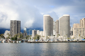 Fototapeta na wymiar Honolulu, Hawaii, USA - May 30, 2016: Yachts docked at Ala Wai Boat Harbour in the Kahanamoku Lagoon against cityscape of Ala Moana.