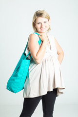 Beautiful happy young blonde pregnant woman with shopping bags posing. Pregnancy, motherhood, sale, people and expectation concept. Isolated on background.