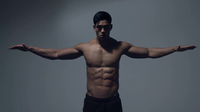 Asian fitness model displaying wingspan. Studio shot. Medium shot. 