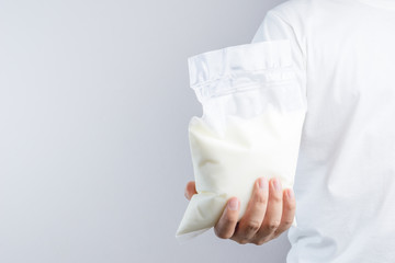 Hand holding a bag of natural yogurt