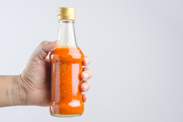 Hand holding spicy red hot sauce in glass bottle for Sukiyaki or hot pot