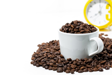 cup with coffee beans and yellow alarm clock on white background, closeup