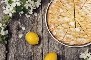 Lemon apple pie, cake sliced on vintage rustic wooden table, decorated flowering branches apple tree. Top view. Selective focus 