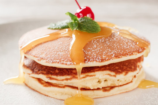 American pancakes with honey topping. Cooking food. Crepe with cherry on white plate background. Traditional US meal.