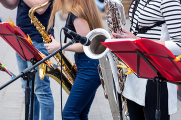 band of young saxophone  players performing during music fest in the city street 