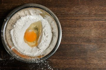 Egg and flour mix in plate on wooden table. Baking process concept, wooden background with copy space