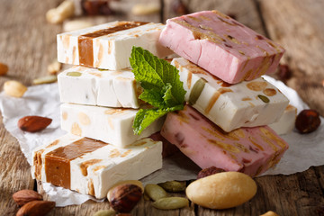White, pink and brown nougat with nuts and mint closeup. Horizontal, rustic 