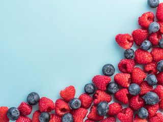 Raspberry and blueberry on blue background with copy space