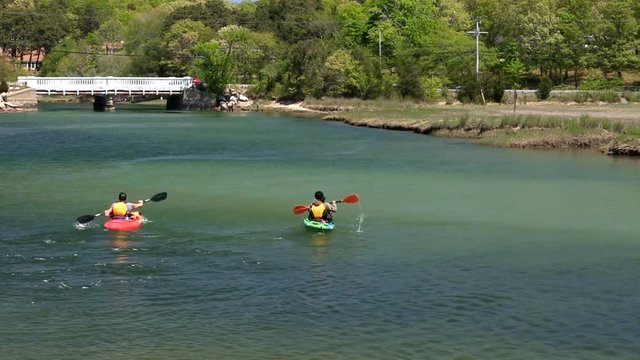 Husband and wife paddling kayaks down stream for sightseeing adventure on scorton creek Sandwich Cape Cod