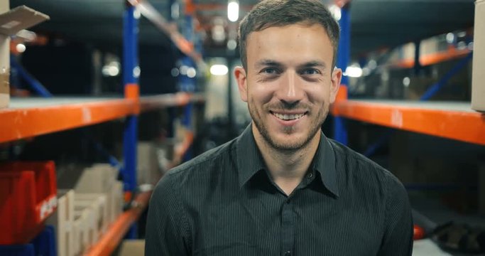 Closeup portrait of smart attactive businessman smiling gently at the warehouse, perspective