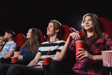 Low angle shot of happy young people smiling enjoying watching a movie at the cinema comedy premiere film spectators audience emotions positivity entertain concept.