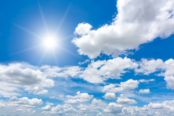 Naklejka na ściany i meble Sun with lens flare in blue sky above clouds.