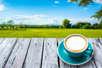 Fresh coffee in cup on old wooden table and beautiful rice field landscape