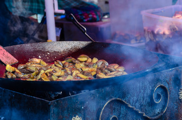 Potato preparing in a big black cauldron