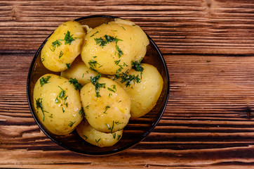 Boiled young potatoes in glass bowl on wooden table. Top view