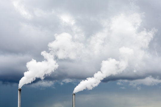 Industrial smoke emission from factory chimney under a stormy sky.