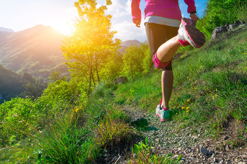 Detail of the legs of a girl running on a mountain trail