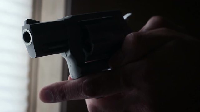 Thriller film concept - chrome revolver is raised off camera
