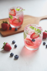 Strawberry juice cocktail with ice and mint on white tone amd wooden