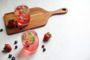 Strawberry juice cocktail with ice and mint on white tone amd wooden