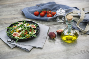 Fresh salad with arugula tomato and cheese on wooden background