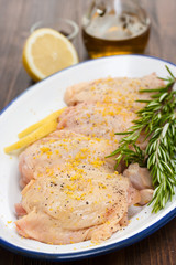 raw chicken with lemon and rosemary on white dish