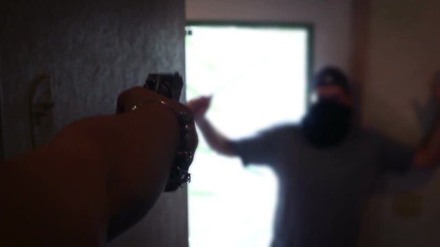 Female housewife aims revolver at instruding criminal in her home