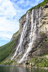 Fototapeta na wymiar Seven Sisters Waterfall in Geiranger Fjord, Norway. It consists of seven separate streams, and tallest of seven has a free fall that measures 250 metres