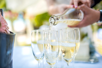 Bride and groom pour into a glass of champagne at a wedding ceremony.