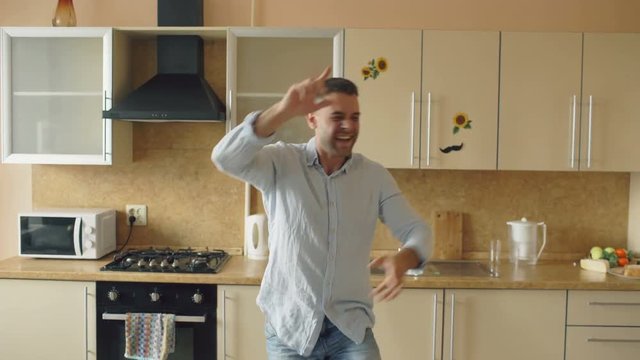 Handsome young funny man dancing in kitchen at home in the morning and have fun on holidays