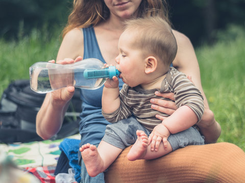 Young mother offering baby drink of water