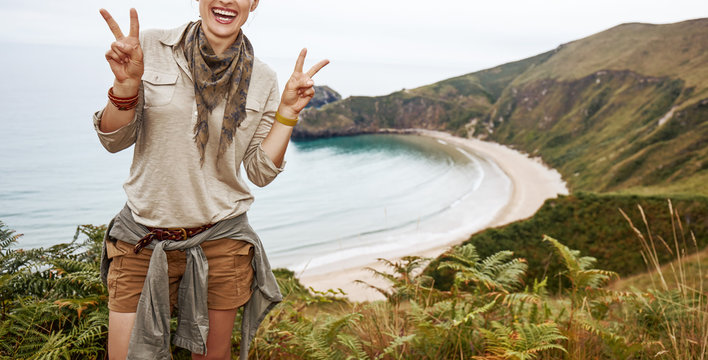 woman hiker showing victory in front of ocean view landscape