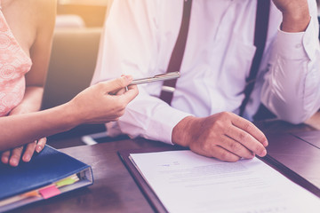 secretary offering pen to her boss for sign contract