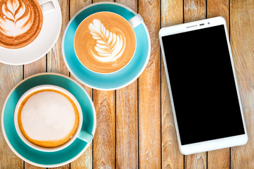 Top view hot Coffee in cup and Smart phone on Wooden table.