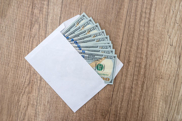 Dollars lie in envelope on wooden desk. concept of bribery or corruption.