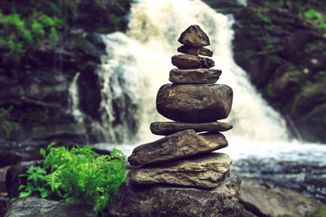 Stone pyramid near a tropical waterfall.
