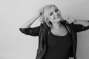 Fototapeta premium A blonde girl on a white background in a black leather jacket expresses her emotions and feelings (joy, sadness, amorousness, femininity, sensuality, tenderness)