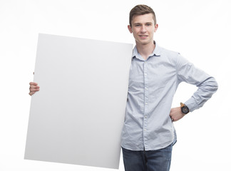 Young glad man portrait of a confident businessman showing presentation, pointing paper placard gray background. Ideal for banners, registration forms, presentation, landings, presenting concept.