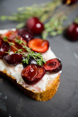 Bread with ricotta cheese and cherries on the wooden background. Shallow depth of field.