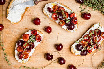 Bread with ricotta cheese and cherries on the wooden background. Shallow depth of field.