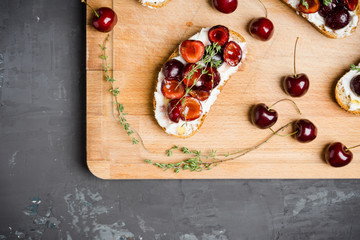 Bread with ricotta cheese and cherries on the wooden background. Shallow depth of field.