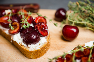 Fototapeta na wymiar Bread with ricotta cheese and cherries on the wooden background. Shallow depth of field.