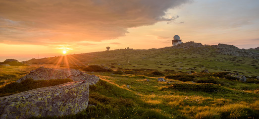 First rays of the summer sun, under dark stormy clouds - beautiful sunrise on a mountain top - July...