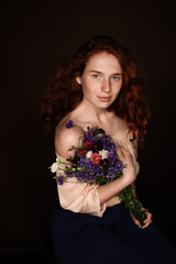 beautiful tender redhead girl posing with bouquet of wild flowers, isolated on black
