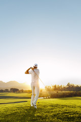 Young man playing golf on a sunny day - obrazy, fototapety, plakaty